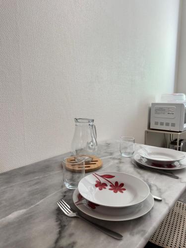 a table with two plates and a glass vase at Studio cosy & pratique avec parking privé in Égletons
