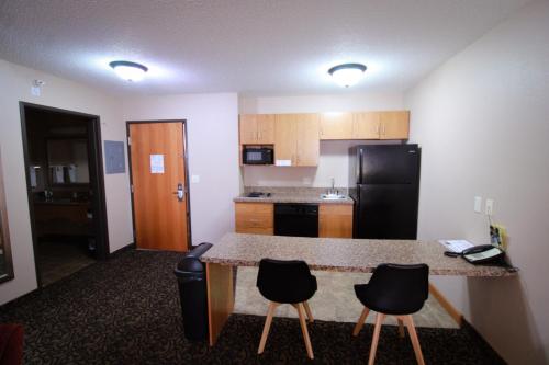 a kitchen with a counter and chairs in a room at Canby Inn and Suites in Canby