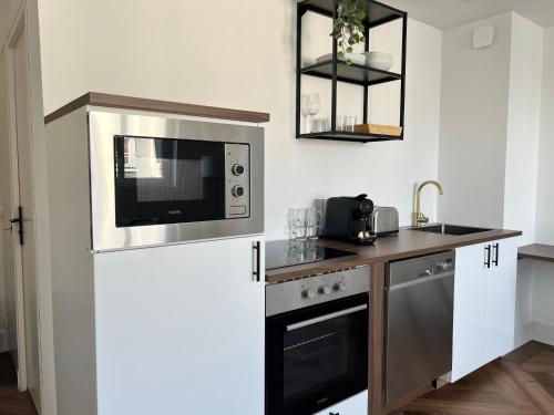 une cuisine avec un micro-ondes et une cuisinière dans l'établissement La suite - King bed - Spacieux - Calme, à Arras