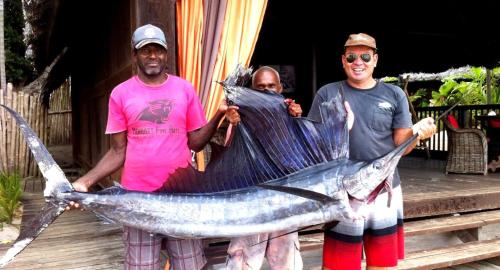two men holding a fish in a net at Ratua Private Island Resort in Aimbuei Bay