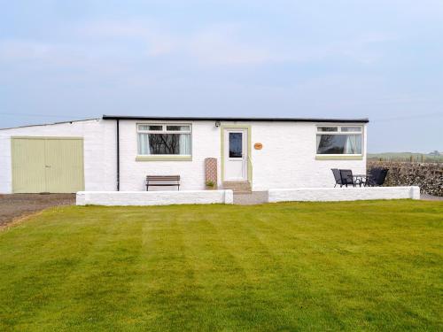 a white house with a lawn in front of it at Mid Bishopton Cottage - Uk10910 in Whithorn