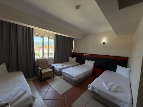 a hotel room with two beds and a chair at Güldal Hotel in Marmaris