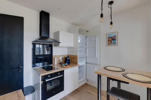 La cuisine est équipée de placards blancs et d'un four avec plaques de cuisson noires. dans l'établissement Le sud cosy- centre -proche gare, à Brive-la-Gaillarde