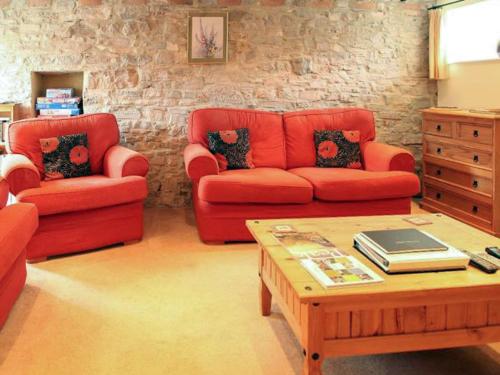 a living room with a red couch and a coffee table at Milkmaids Cottage-Uk31860 in Kniveton
