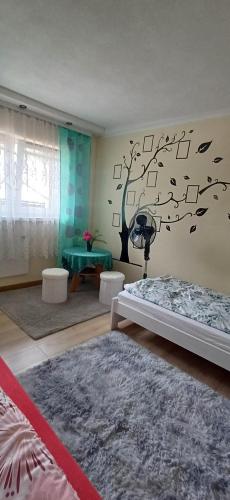 a bedroom with two beds and a tree on the wall at Pod Górą in Wiśniowa