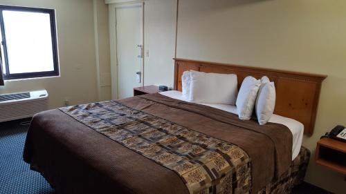 a hotel room with a large bed with white pillows at Royal Inn in Tonawanda
