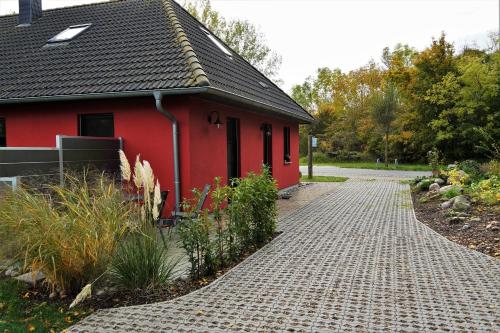 a red house with a cobblestone road in front of it at Ferienhaus Am Pappelwald in Glowe