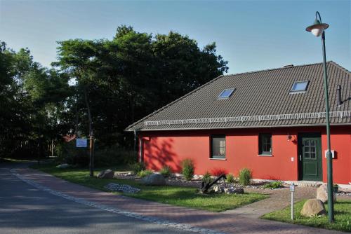 a red house on the side of a road at Ferienhaus Am Pappelwald in Glowe
