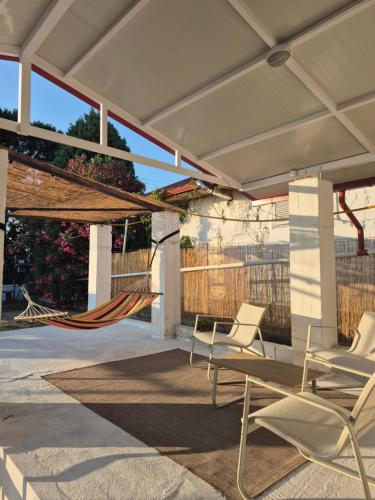 a patio with chairs and a hammock on it at Villa Aspri in Nea Kalikratia