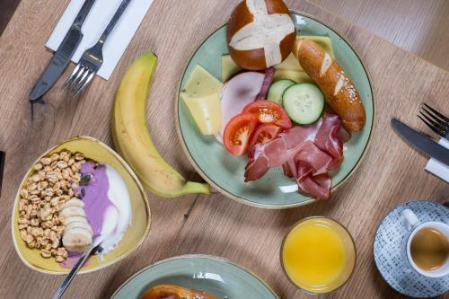 two plates of food on a wooden table with breakfast foods at Garner Hotel Cologne - Engelbertz by IHG in Cologne