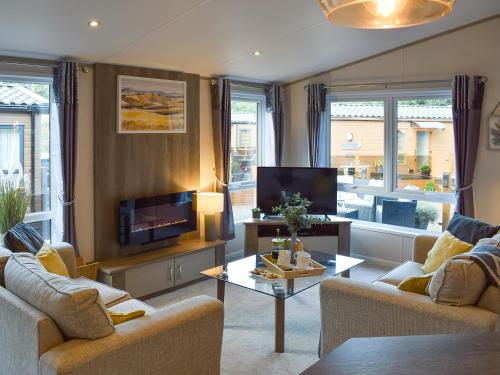 Una sala de estar con dos sofás y un televisor. en Riverside Lodge, en Auchterarder
