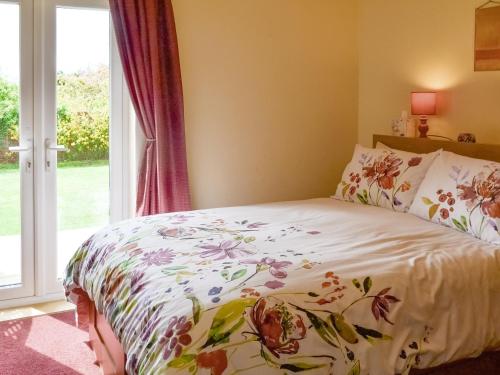 a bedroom with a bed with a floral bedspread at 1 34 Denwick View in Alnwick