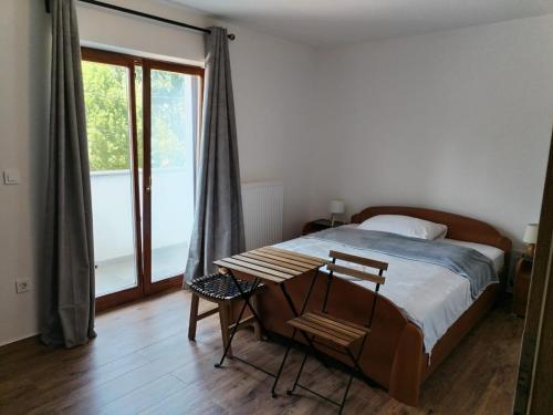 a bedroom with a bed and a table and a window at Villa Roko in Ličko Lešće