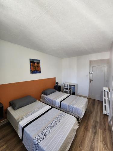 deux lits dans une chambre aux murs blancs et au parquet dans l'établissement Grand appartement vue sur la Cité !, à Carcassonne