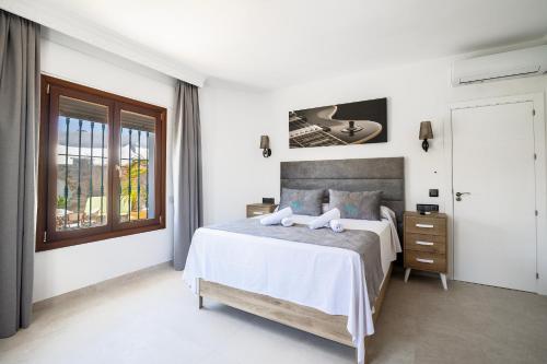 a white bedroom with a bed and a window at Hotel Boutique Zahara in Zahara de los Atunes