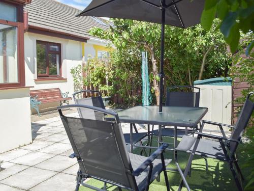 ein Tisch und Stühle mit einem Sonnenschirm auf einer Terrasse in der Unterkunft Pembroke Cottage in Pembroke