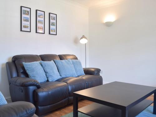 ein Wohnzimmer mit einem braunen Sofa und einem Tisch in der Unterkunft Pembroke Cottage in Pembroke