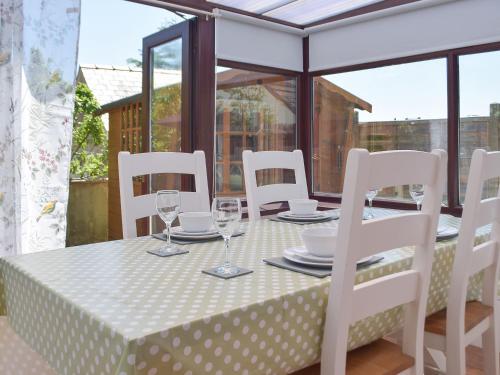 a table with white chairs and a table with glasses at Pembroke Cottage in Pembroke