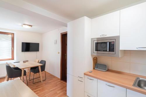 kuchnia z białymi szafkami i stołem z krzesłami w obiekcie Apartmán Hotel Vomočil Bystré w mieście Bystré