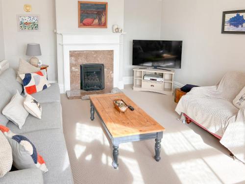 Una sala de estar con un sofá y una chimenea. en Grey Croft, en Christon Bank