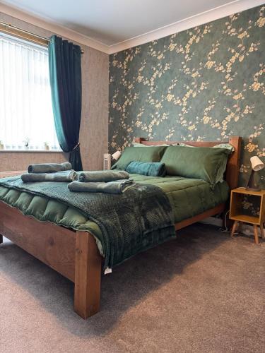 a bedroom with a large bed with a green comforter at Ash Cottage in Tollerton