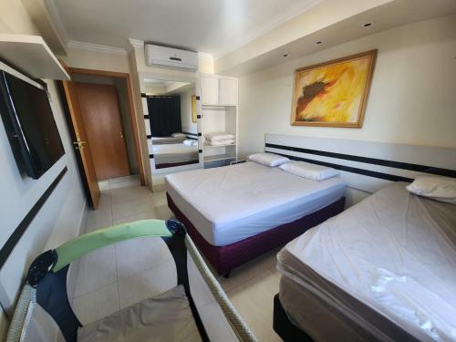 a hotel room with two beds and a chair at Apartamento Giardino Rio Quente in Rio Quente