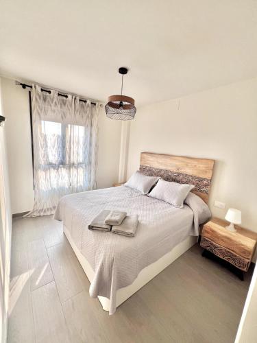 a white bedroom with a large bed and a window at Top apartment! in Benajarafe