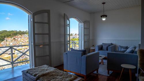 salon z niebieskimi krzesłami i dużym oknem w obiekcie Casa com lareira, Wi-Fi e varanda com vista w mieście Campos do Jordão