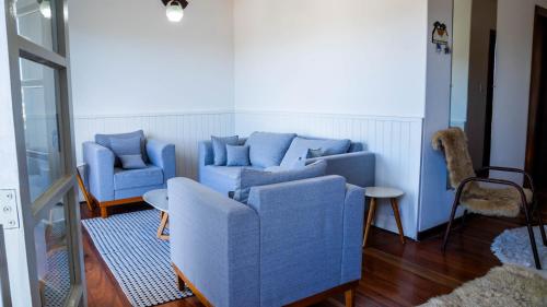 salon z dwiema niebieskimi kanapami i stołem w obiekcie Casa com lareira, Wi-Fi e varanda com vista w mieście Campos do Jordão