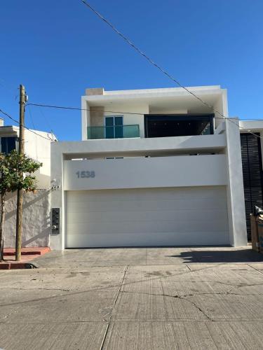 a house with a white garage door and aphalt at QC Departamento privado de lujo en Quintas in Culiacán