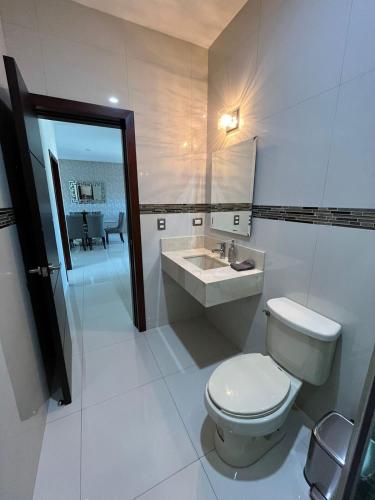 a white bathroom with a toilet and a sink at QC Departamento privado de lujo en Quintas in Culiacán