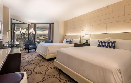 a hotel room with two beds and a desk at Harrah's Las Vegas, A Caesars Destination in Las Vegas