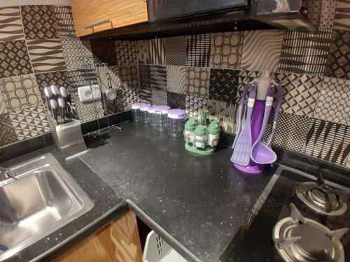 a kitchen counter with a sink and a counter top with bottles at شقه فندقيه اول سكن in Cairo