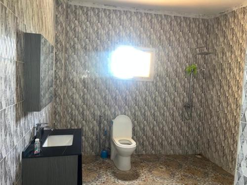 a bathroom with a toilet and a sink and a window at Peace apartment in Brufut