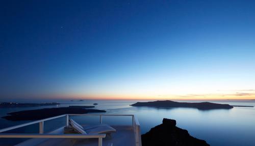 a room with a view of the ocean at dusk at Whitedeck Santorini in Imerovigli