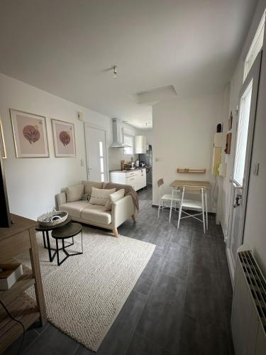 a living room with a couch and a table at A l'ombre du Marronnier in Préfailles