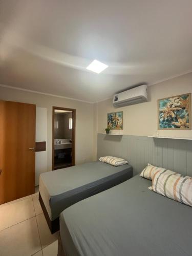 a bedroom with two beds and a air conditioner at Bangalô 39 in Tamandaré
