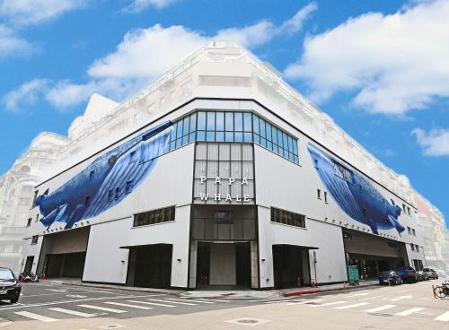 a large white building with blue windows on a street at Hotel PaPa Whale in Taipei