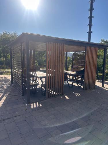 a wooden pavilion with a picnic table and benches at Easy Rest in Tbilisi City