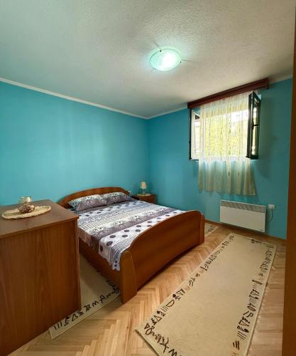 Un dormitorio con una cama y una pared azul. en Ninas Apartment, en Marovići