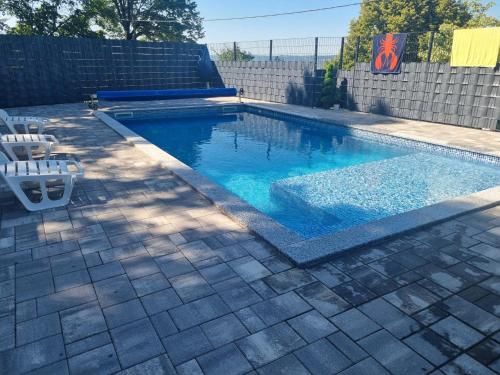 a swimming pool in a yard with two chairs at Vikendica Artos in Bihać