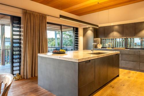 cocina con fregadero y ventana grande en Moa Whare - Stay Waiheke, en Waiheke Island