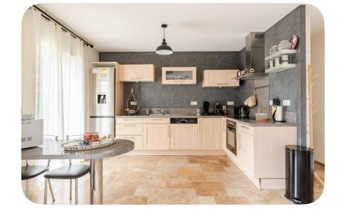 une cuisine avec des armoires blanches et une table à l'intérieur dans l'établissement GITE Thiron Gardais LA COUR aux PAUVRES, à Thiron-Gardais