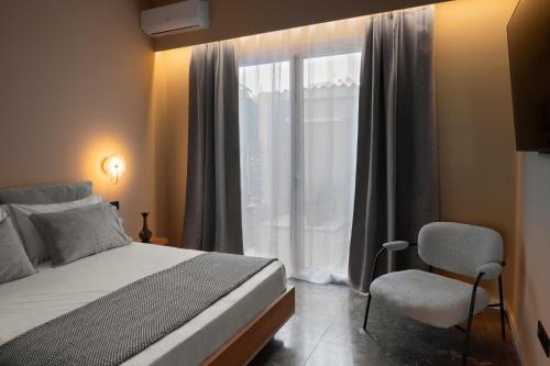 a bedroom with a bed and a window and a chair at Tproject in Preveza