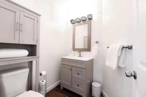 a white bathroom with a sink and a mirror at Chain O' Lakes Beach Penthouse Sunset View and Boat Dock 