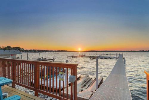 a dock on a lake with the sunset in the background at Chain O' Lakes Beach Penthouse Sunset View and Boat Dock 