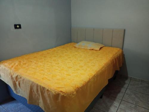 a small bed in a room with a yellow sheet at Pé na roça in Camanducaia