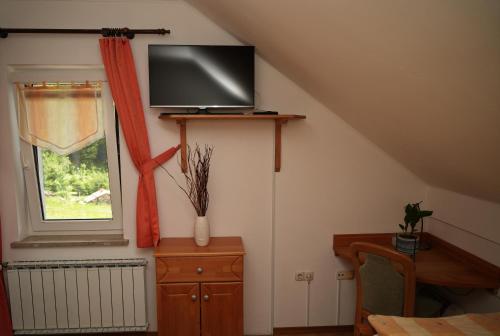 a room with a tv on a wall with a window at Miškar Rooms in Cerknica