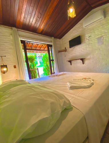 a bedroom with a white bed with a tv on the wall at Pousada Praia da Pipa in Pipa