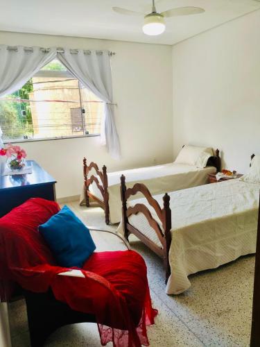 a bedroom with two beds and a chair and a window at Solar Martins Lobato in Pedro Leopoldo